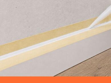 Aanbrengen van kit langs een plint met afplaktape