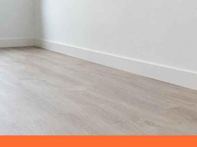 Groot vraagteken op een vloer naast een witte plint in een modern interieur, als illustratie van een vraag over plinten monteren of afwerken.