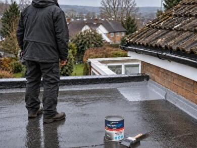 Applying emergency waterproof roof coating to a flat roof to seal leaks and prevent water ingress