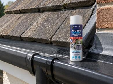 Waterproof roof coating and waterproofing spray displayed on a flat roof and roof gutter for emergency leak repairs