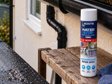 Bostik Waterstop Emergency Waterproof Coating with brush applying waterproof coating to a flat roof for emergency leak repair