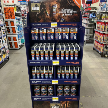 Présentoir en magasin rempli de produits Mamut, organisé par gamme pour guid­er les clients dans l’achat de solutions de collage, fixation et étanchéité.