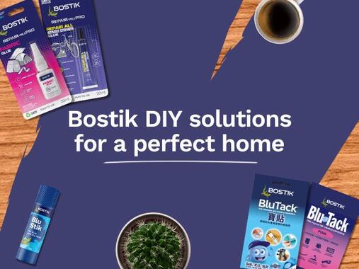 Bostik DIY home improvement banner featuring Repair All and Fabric Glue products, Blu Stick adhesive, Blu Tack products, a coffee cup, and a potted cactus on a wooden background with the message "Bostik DIY solutions for a perfect home.