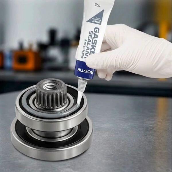 Close-up of Bostik Gasket Sealant RTV Silicone Grey being applied to a metal bearing assembly, creating a continuous seal around a circular component for gasket sealing and leak prevention.